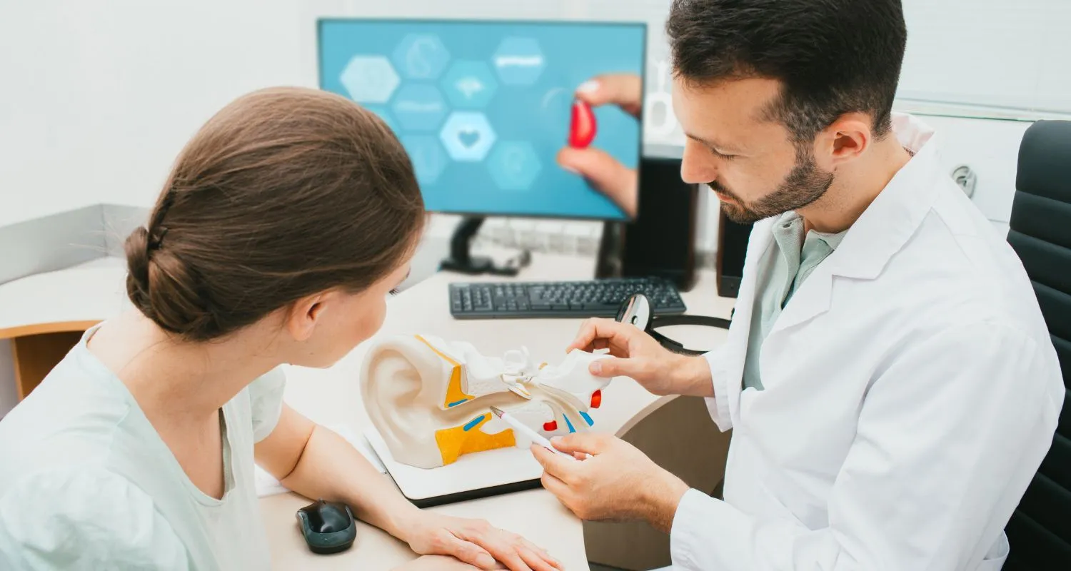 Audiologist showing patient model of ear