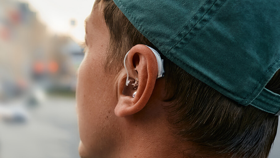 Side rear view of man with hat and hearing aid